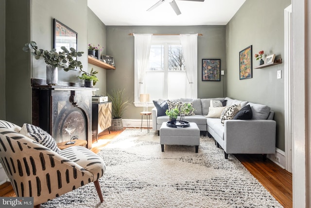 living area featuring baseboards, wood finished floors, and a ceiling fan