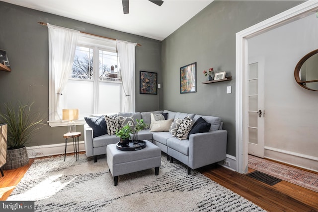 living room featuring ceiling fan, visible vents, baseboards, and wood finished floors