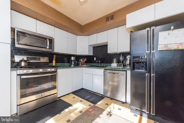 kitchen featuring visible vents, a sink, dark countertops, stainless steel appliances, and white cabinets