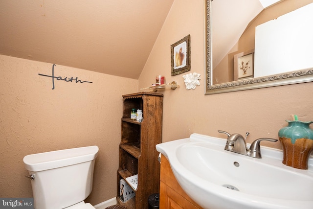 half bath featuring a sink, lofted ceiling, and toilet