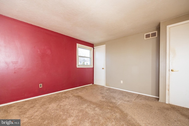 carpeted spare room featuring visible vents and a textured ceiling