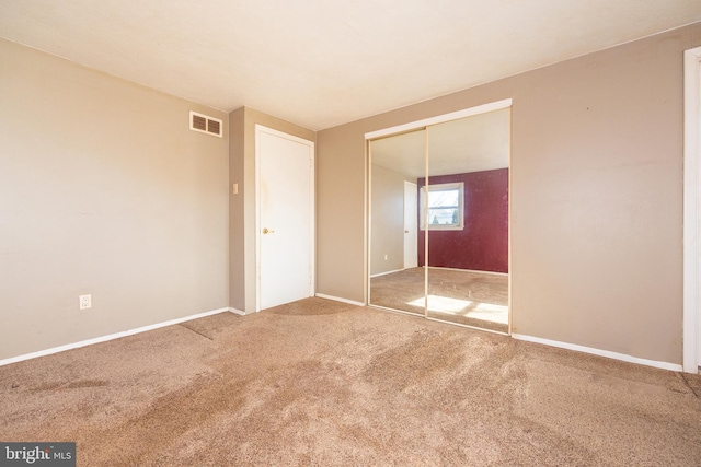 unfurnished bedroom featuring baseboards, visible vents, a closet, and carpet floors