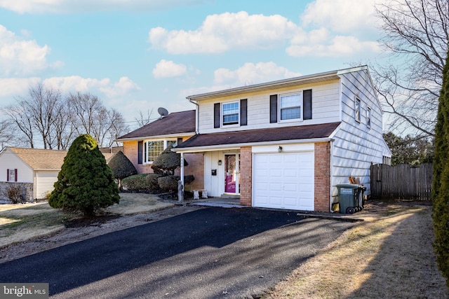 view of front facade with brick siding, an attached garage, aphalt driveway, and fence