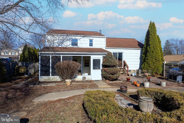 back of house featuring entry steps, fence, and a sunroom