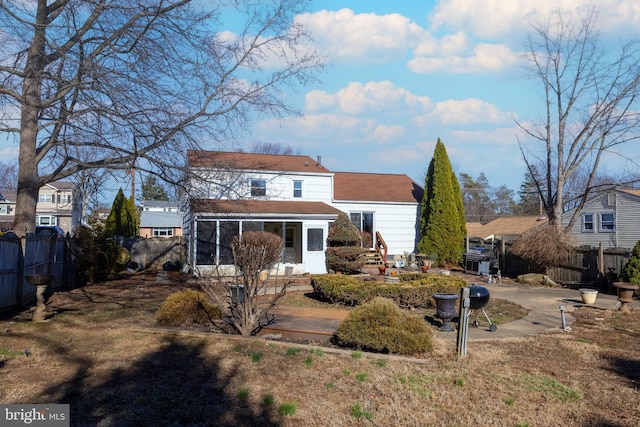 back of property featuring a sunroom and fence