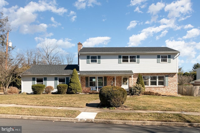 view of front facade featuring a front yard, fence, brick siding, and a chimney