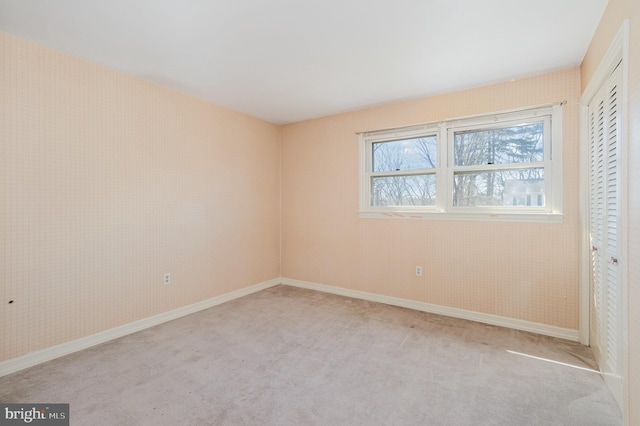 unfurnished bedroom with light colored carpet, a closet, and baseboards