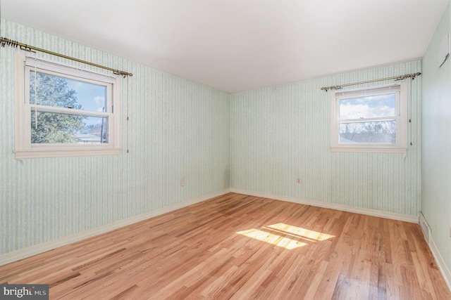 empty room featuring wallpapered walls, wood finished floors, and baseboards