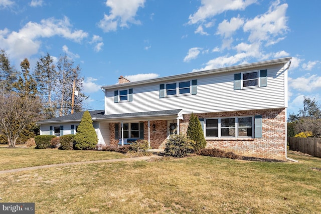 view of front of home with a front yard, fence, brick siding, and a chimney