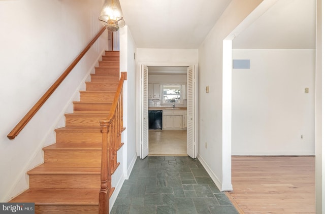 staircase featuring baseboards and stone finish floor