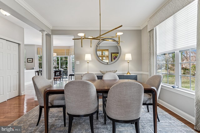 dining space featuring decorative columns, baseboards, wood finished floors, and crown molding