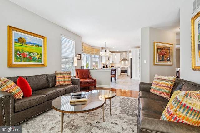 living area with light wood-style floors and an inviting chandelier