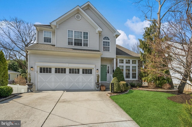 traditional-style house with driveway, fence, a front yard, a shingled roof, and a garage