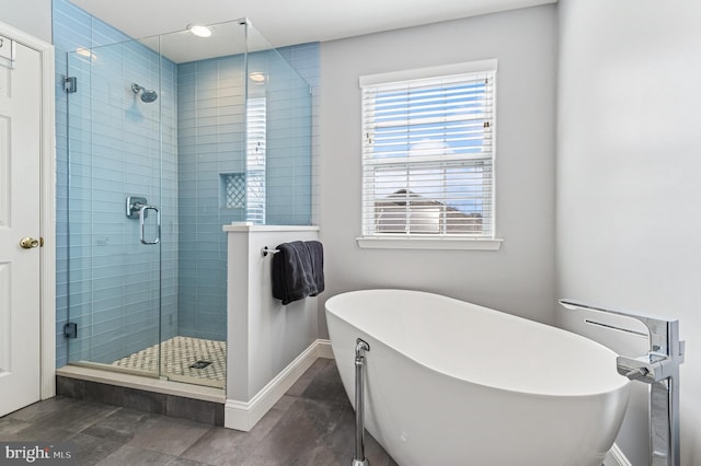 bathroom with a shower stall, a soaking tub, and baseboards