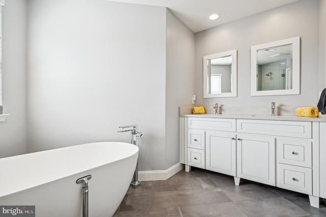 full bathroom featuring double vanity, a sink, a shower, baseboards, and a soaking tub