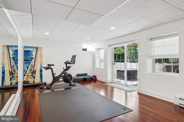 workout room with a drop ceiling, baseboards, wood finished floors, and a baseboard radiator