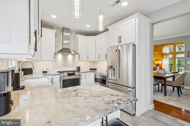 kitchen featuring light stone counters, visible vents, a sink, stainless steel appliances, and wall chimney range hood