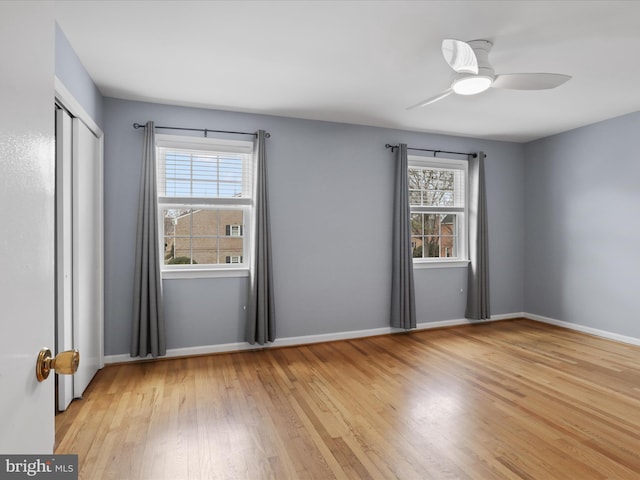 unfurnished bedroom featuring a closet, ceiling fan, baseboards, and wood finished floors