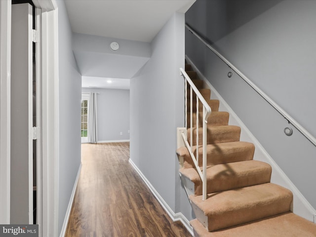 staircase featuring wood finished floors and baseboards