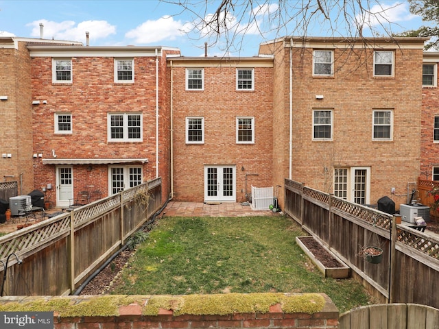 rear view of property featuring central AC unit, a yard, french doors, and brick siding