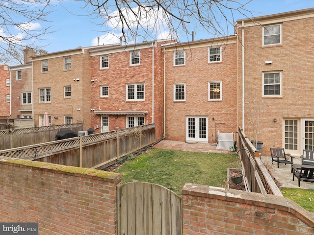 back of property featuring brick siding, fence private yard, french doors, a patio, and a gate