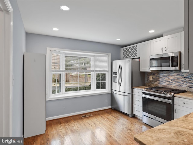 kitchen with visible vents, backsplash, light wood-style floors, appliances with stainless steel finishes, and light countertops