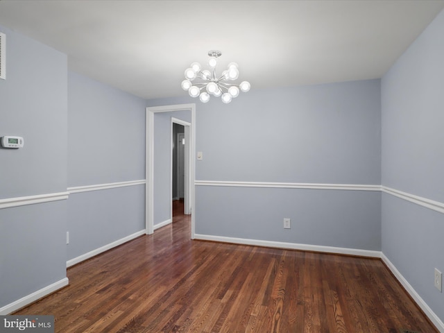 unfurnished room with a notable chandelier, baseboards, and wood finished floors