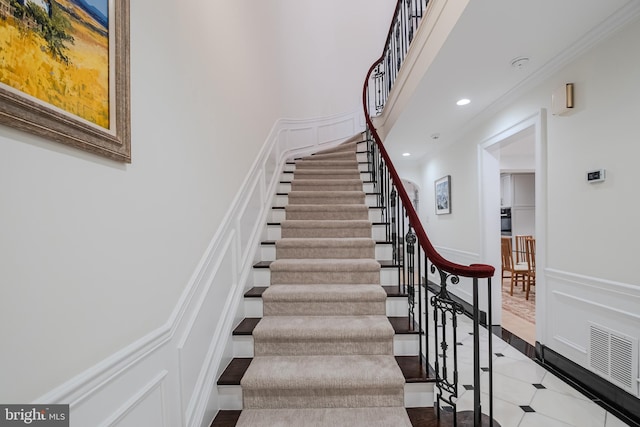 stairway with visible vents, crown molding, wainscoting, recessed lighting, and a decorative wall