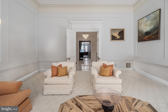 living area featuring a decorative wall, visible vents, baseboards, and ornamental molding