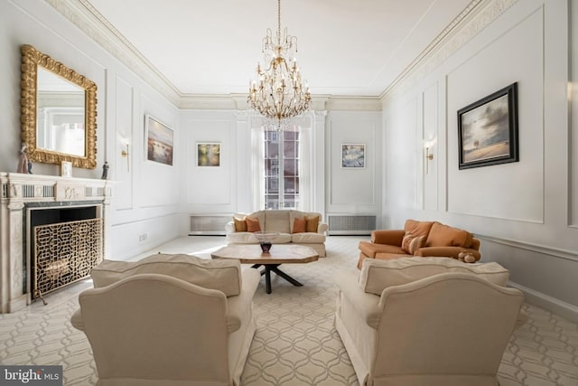 living area with a chandelier, a decorative wall, a fireplace, and ornamental molding