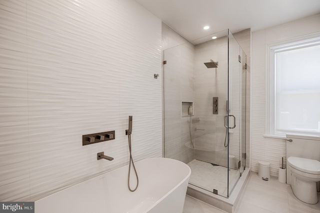 bathroom featuring a freestanding tub, toilet, a stall shower, recessed lighting, and tile walls