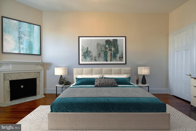 bedroom featuring wood finished floors, baseboards, and a premium fireplace