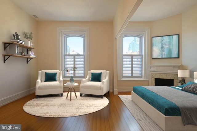 bedroom with visible vents, multiple windows, a fireplace, and hardwood / wood-style flooring