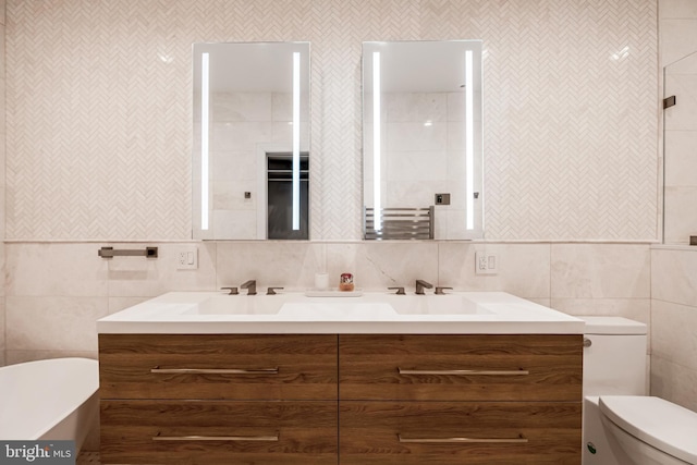 bathroom with double vanity, a freestanding tub, and toilet