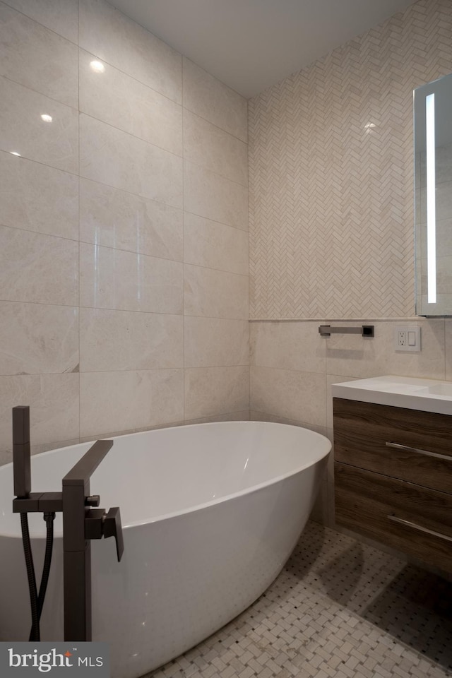 bathroom with a freestanding bath, tile walls, and vanity