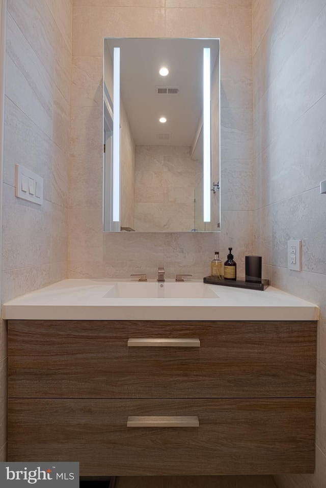 bathroom featuring visible vents, tile walls, and vanity