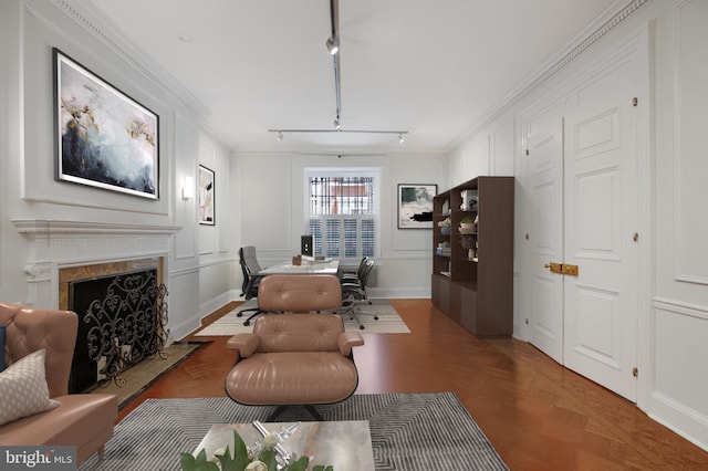 office space with wood finished floors, a decorative wall, rail lighting, crown molding, and a fireplace