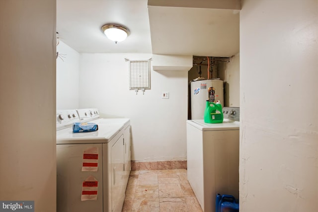 laundry area featuring laundry area, stone finish flooring, water heater, and washer and clothes dryer