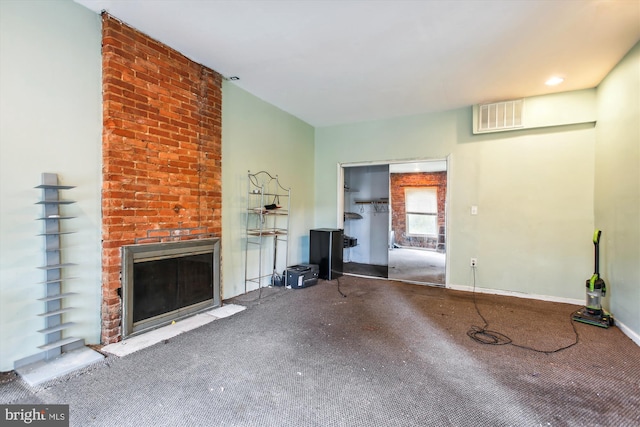 unfurnished living room with a brick fireplace, baseboards, visible vents, and carpet floors