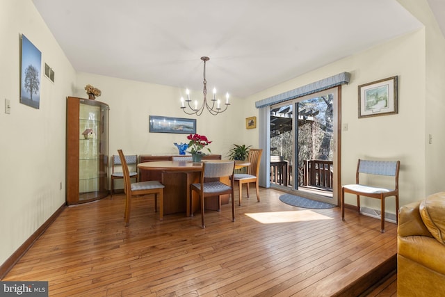 dining room featuring a notable chandelier, baseboards, visible vents, and wood-type flooring