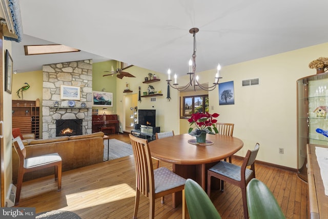 dining area with light wood-style floors, lofted ceiling, a fireplace, and visible vents