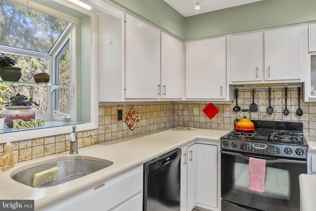 kitchen featuring black range with gas stovetop, light countertops, dishwashing machine, white cabinetry, and a sink