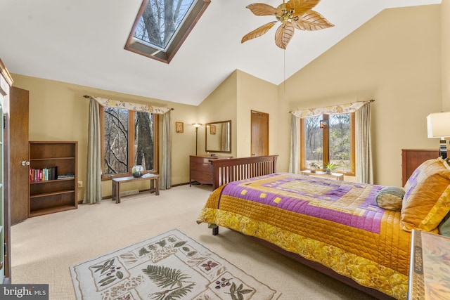 bedroom featuring a ceiling fan, high vaulted ceiling, a skylight, and carpet flooring