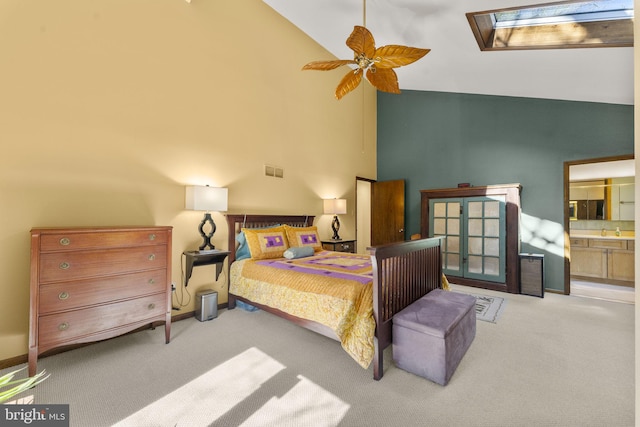 carpeted bedroom with baseboards, visible vents, high vaulted ceiling, a skylight, and ensuite bathroom