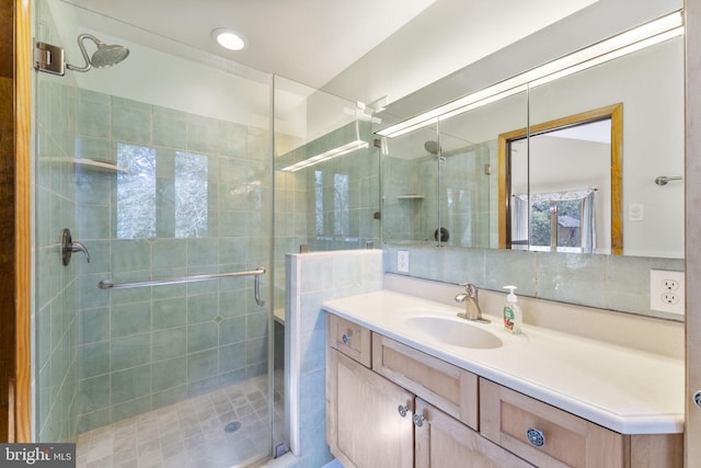 bathroom featuring backsplash, a shower stall, and vanity