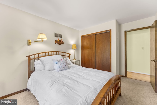 bedroom featuring light colored carpet, baseboards, visible vents, and a closet