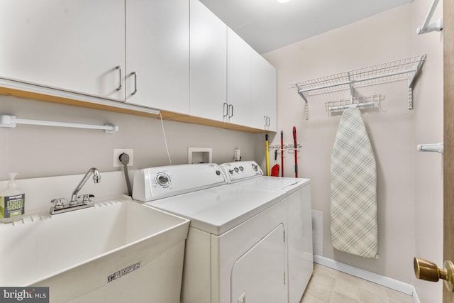 washroom with washing machine and dryer, cabinet space, baseboards, and a sink