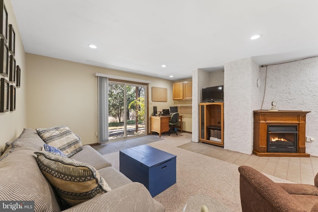 living room featuring recessed lighting, light carpet, and a lit fireplace