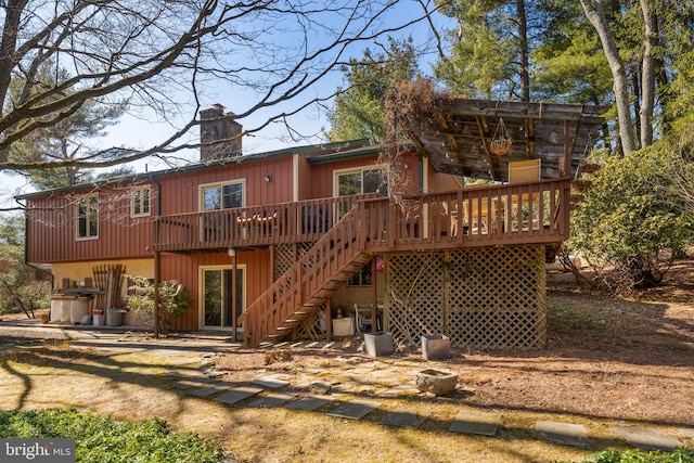 back of property featuring stairway, a chimney, and a deck