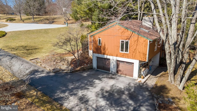 view of home's exterior with a garage, a lawn, and driveway